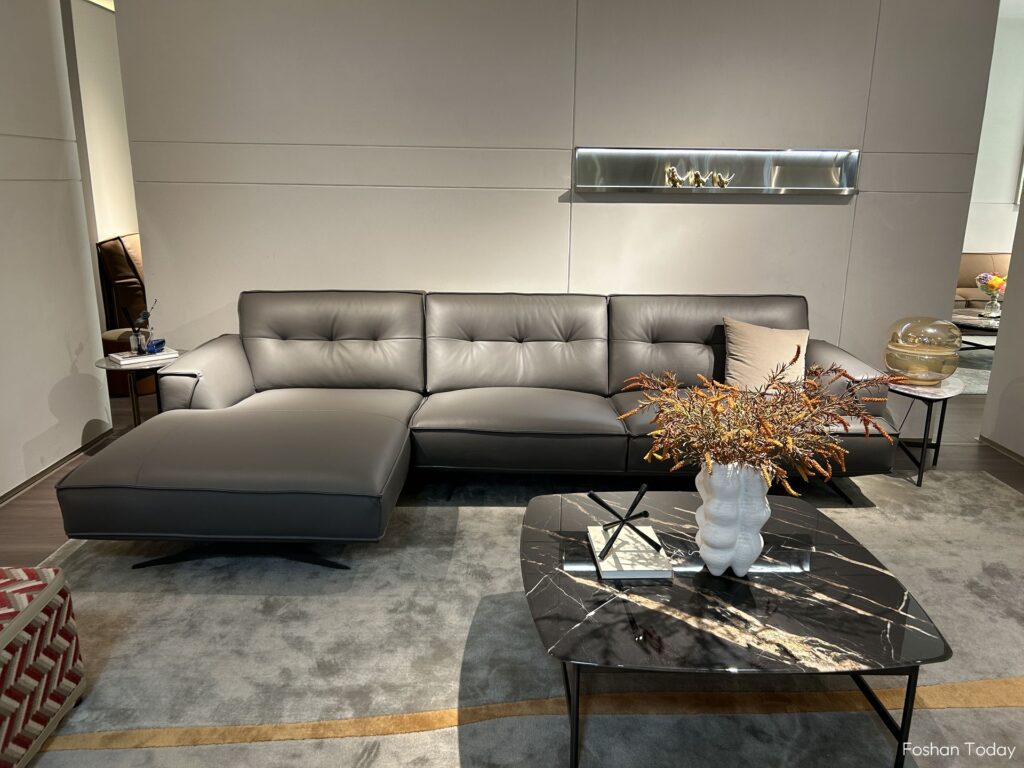 The dark gray L-shaped leather sofa and the marble coffee table